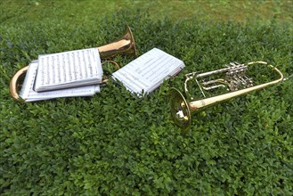 Wind instruments with sheet music laid down on a hedge in the break of the band