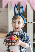 Adorable little boy holding basket with easter eggs