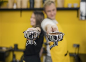 Baristas posing back back while holding cups