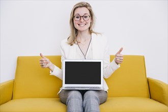Cheerful woman with laptop gesturing thumb up