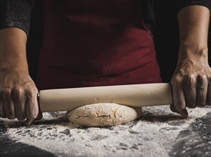 Close up baker rolling dough composition
