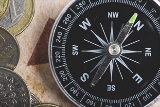 Close up black compass with some coins