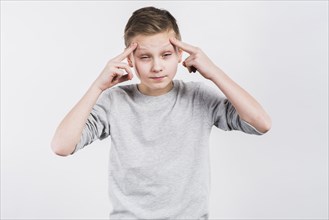Close up boy suffering from headache against grey background