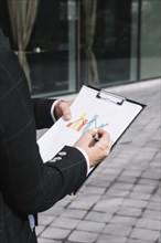 Close up business person s hand drawing increasing arrow graph clipboard
