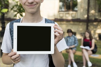Close up highschool boy holding tablet hands