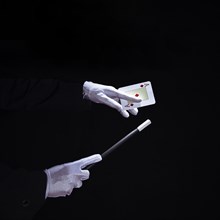 Close up magician performing trick playing card with magic wand