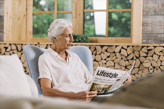 Close up woman sitting chair reading newspaper