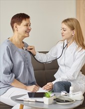 Covid recovery center female doctor checking elder patient s heartbeat with stethoscope