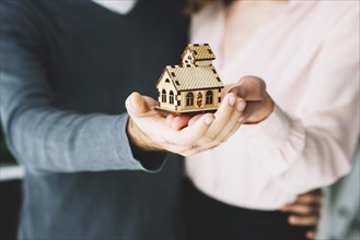 Crop couple holding toy house