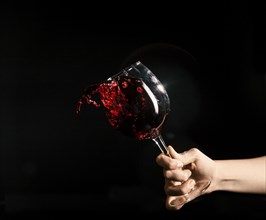 Crop hand splashing wine from glass