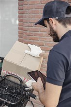 Delivery man with parcel using digital tablet