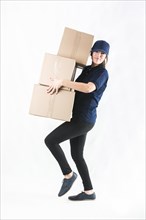 Delivery woman carrying stacked courier boxes against white background