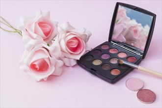 Fake pink flowers with blusher eyeshadow palette with makeup brush