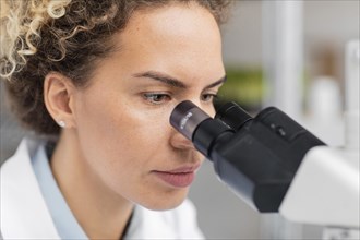 Female researcher laboratory looking through microscope