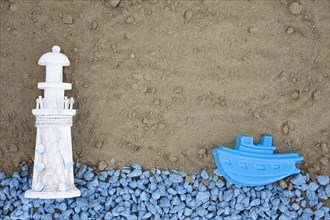 Flat lay blue pebbles with lighthouse boat sand