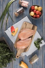 Flat lay chicken breast wooden board with peppers tomatoes