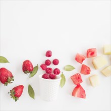 Fresh raspberries spilled front glass with strawberry watermelon pineapple isolated white background