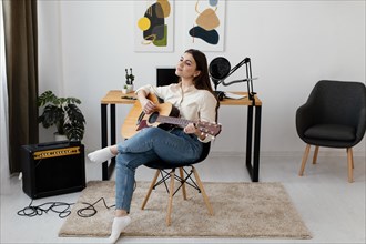 Front view female musician playing acoustic guitar home