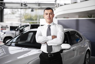 Front view male car dealer standing with arms crossed