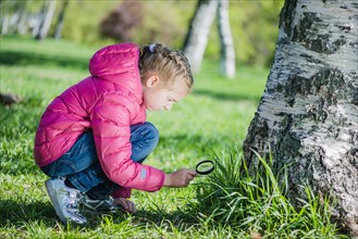 Girl analyzing lawn with magnifying glass