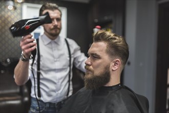 Hairdresser using drier hair client