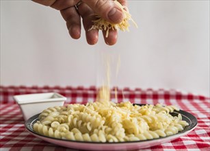 Hand sprinkling cheese pasta