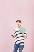 Happy young man with whatsapp icon using smartphone
