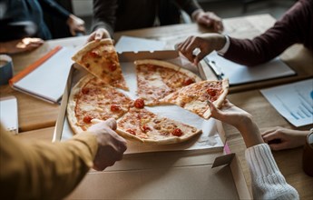 High angle colleagues having pizza during office meeting break