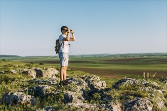 Hiker standing rock looking through binocular