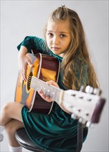 Little girl dress playing acoustic guitar