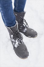 Low section woman standing with winter boots snow