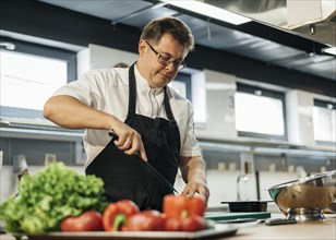 Male chef chopping tomatoes kitchen