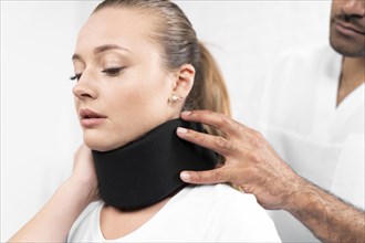 Male physiotherapist putting neck brace woman