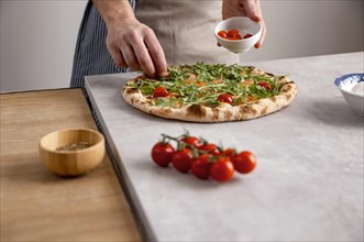 Man putting tomatoes baked pizza dough with smoked salmon slices