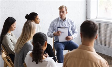 Man showing clipboard group therapy session