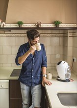 Man standing kitchen drinking coffee