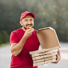 Medium shot delivery guy eating pizza