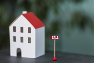 Miniature model house real estate sale against blurred backdrop