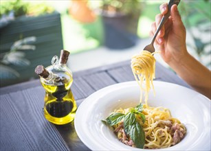 Olive oil bottle with person holding spaghetti with fork