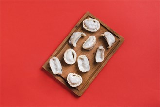 Overhead view steam dumplings wooden tray against red background
