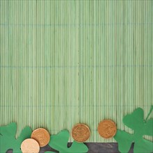 Paper clovers near coins bamboo mat