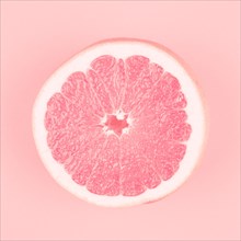 Pink halved fresh juicy grapefruit pink background