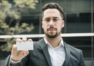 Portrait young businessman showing blank white business card