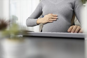 Pregnant businesswoman office desk holding her belly
