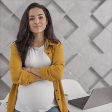 Pregnant woman posing with laptop home