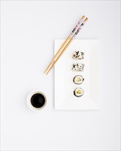 Ready eat sushi rolls white plate with chopsticks soy sauce isolated white background