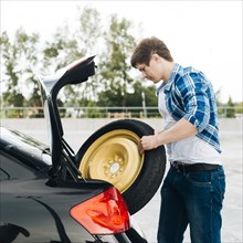 Side view man taking out spare tire