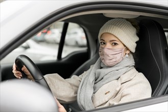 Side view woman driving with medical mask