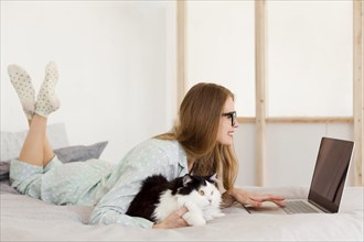 Side view woman working pajamas from home with cat
