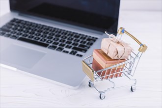 Small grocery cart with gift boxes laptop